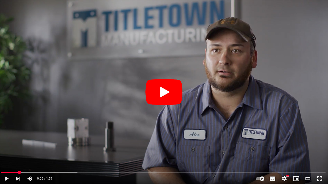 Employee interview at Titletown Manufacturing, featuring a man in a blue striped work shirt discussing his role and experiences in the manufacturing industry, with company branding visible in the background.