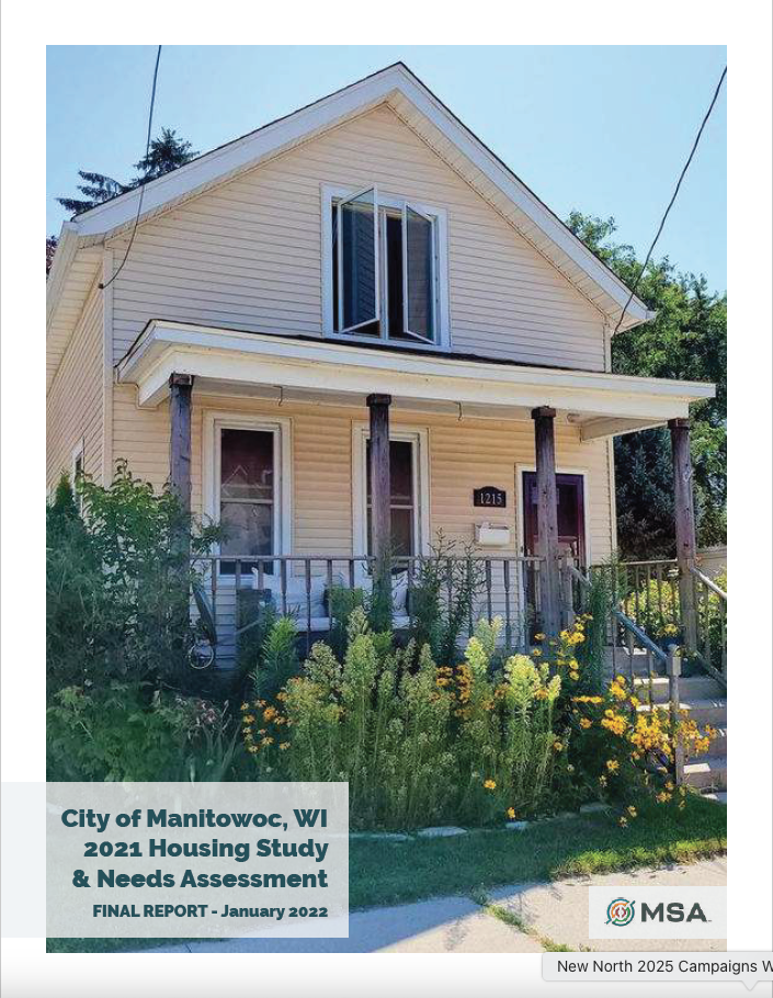 Front view of a yellow two-story house located at 1215 in Manitowoc, WI, surrounded by greenery and flowers, featured in the 2021 Housing Study and Needs Assessment report.