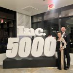 Couple posing at the Inc. 5000 event with large decorative sign displaying "Inc. 5000" in a stylish venue, showcasing celebration of business achievements.